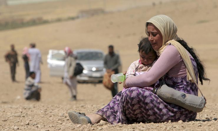 A Yazidi mother holding onto her child after ISIS terrorized their towns of Sinjar mountain - Iraq